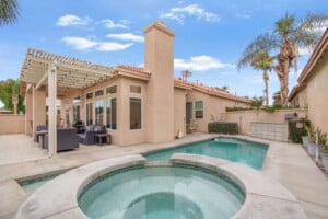 Pool and spa with covered patio and palm trees